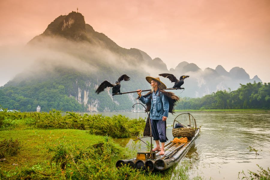 pescador sobre canos en yangshuo con montana de fondo
